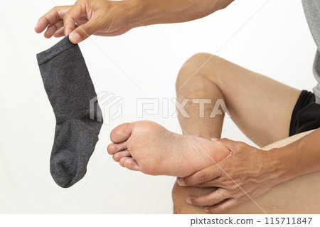 A man's hand holding a sock on a white background 115711847