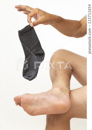 A man's hand holding a sock on a white background A man's hand holding a sock on a white background 115711854