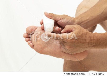 一個男人在腳底塗奶油，白色背景 115711857