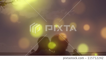 Glowing spots of light falling against african american couple kissing each other at the beach Glowing spots of light falling against african american couple kissing each other at the beach 115712242