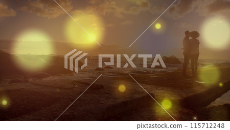 Glowing yellow spots of light falling against african american couple standing together on the rocks 115712248