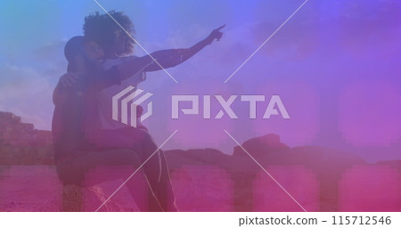 Pink square pattern over african american couple pointing towards a direction sitting on the rocks Pink square pattern over african american couple pointing towards a direction sitting on the rocks 115712546
