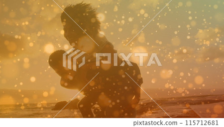 Orange spots of light against african american man giving his wife a piggyback ride at the beach Orange spots of light against african american man giving his wife a piggyback ride at the beach 115712681