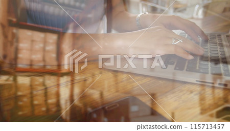 Image of woman typing on computer keyboard with stacks of boxes in warehouse 115713457