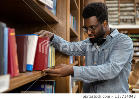 African american young man in the library looking busy and involved African american young man in the library looking busy and involved 115714048