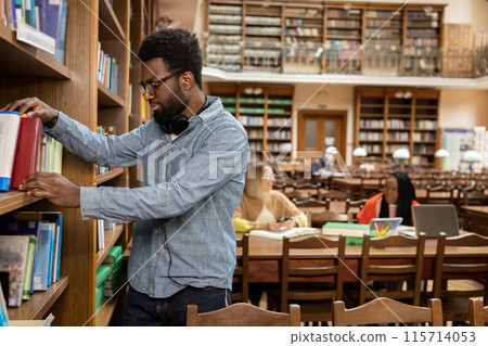 African american young man in the library looking busy and involved 115714053