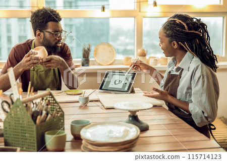 Dark-skinned woman with dreads conducting a ceramics workshop 115714123