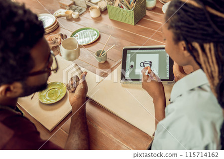 Two people sitting at the table and working with pottery 115714162