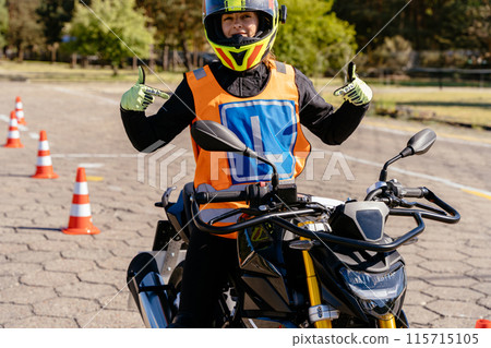 A woman is riding a motorcycle and is wearing a safety vest. She is smiling and giving thumbs up A woman is riding a motorcycle and is wearing a safety vest. She is smiling and giving thumbs up 115715105
