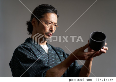一個穿著日本服裝的男人看著陶瓷、陶藝家、鑑賞家的形象 一個穿著日本服裝的男人看著陶瓷、陶藝家、鑑賞家的形象 115715436