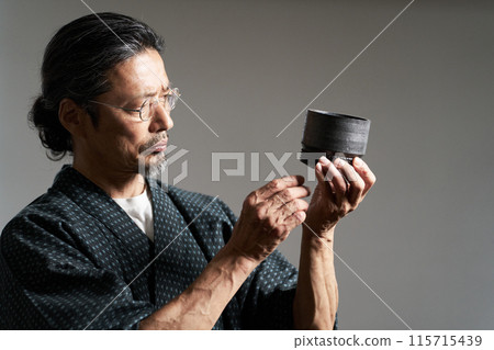 Image of a man in a kimono gazing at ceramics, a ceramic artist, an appraiser 115715439