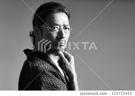 A man in a work uniform looking at something, senior craftsman, monochrome image A man in a work uniform looking at something, senior craftsman, monochrome image 115715455