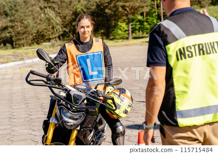 Student and instructor, exam in motorcycle school. Learner biker on test road with red cones. Instructor writing on clipboard his points. 115715484