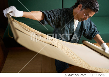 A man in a kimono spreading out a hanging scroll to check it - Appraiser, antique dealer, collector - Image 115715489