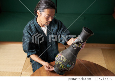 A man in a kimono holding a copper pot to check it - Appraiser, antique dealer, collector Image A man in a kimono holding a copper pot to check it - Appraiser, antique dealer, collector Image 115715529