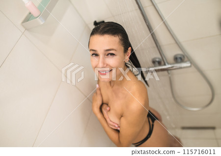 Naked woman having a shower and looking relaxed Naked woman having a shower and looking relaxed 115716011