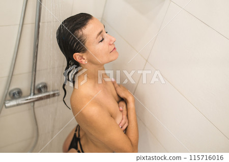 Naked woman having a shower and looking relaxed Naked woman having a shower and looking relaxed 115716016
