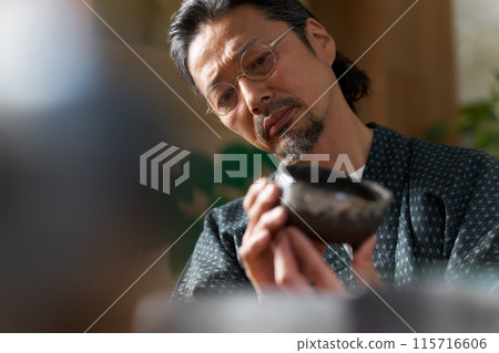 Image of a man in a kimono gazing at ceramics, a ceramic artist, an appraiser Image of a man in a kimono gazing at ceramics, a ceramic artist, an appraiser 115716606