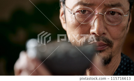 Image of a man in a kimono gazing at ceramics, a ceramic artist, an appraiser 115716613