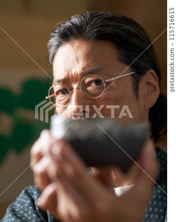 一個穿著日本服裝的男人看著陶瓷、陶藝家、鑑賞家的形象 一個穿著日本服裝的男人看著陶瓷、陶藝家、鑑賞家的形象 115716615