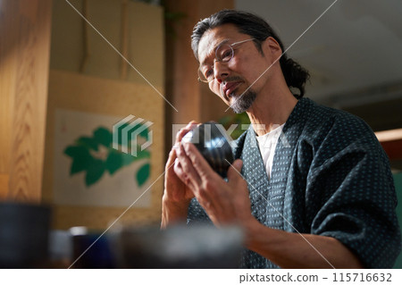 Image of a man in a kimono gazing at ceramics, a potter, an appraiser 115716632