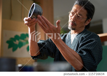 一個穿著日式服裝的男人看著陶瓷、陶藝家、鑑定師的形象 一個穿著日式服裝的男人看著陶瓷、陶藝家、鑑定師的形象 115716634