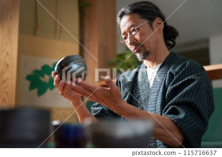 Image of a man in a kimono gazing at ceramics, a potter, an appraiser 115716637