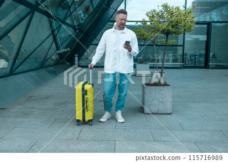 Young Caucasian male passenger in stylish casual clothes using smartphone and laptop keyboard, sit has training online meeting on laptop computer in airline lounge wait transit international airport 115716989
