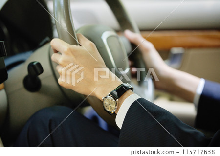 A young man in a suit holding a steering wheel A young man in a suit holding a steering wheel 115717638