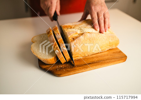 Homemade sourdough bread. Woman hands cuts the bread on cutting board. Handcrafted. Wooden cutting board.  115717994