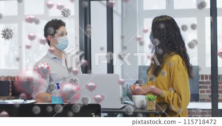 Image of covid 19 cells floating over man and woman wearing face masks, touching elbows in office 115718472