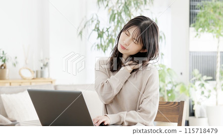 A woman who feels stiff shoulders while working on a computer A woman who feels stiff shoulders while working on a computer 115718479