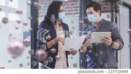 Image of covid 19 cells over colleagues in face masks with digital tablet in office 115718499