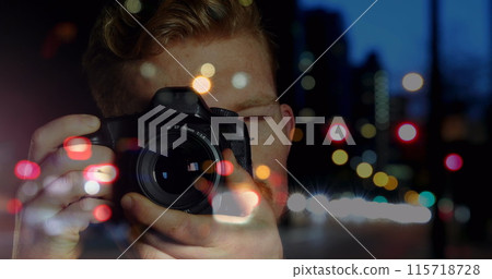 Caucasian male photographer clicking pictures with digital camera against night city traffic 115718728