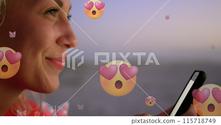 Image of emoticons over profile of happy biracial woman using smartphone at beach 115718749