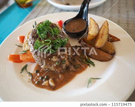 A delicious dinner plate with grilled beef steak and colorful vegetables cooked in a savory sauce 115719475