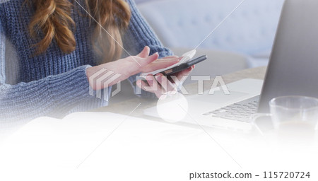 Image of white spots over caucasian woman wiping smartphone using laptop at home Image of white spots over caucasian woman wiping smartphone using laptop at home 115720724
