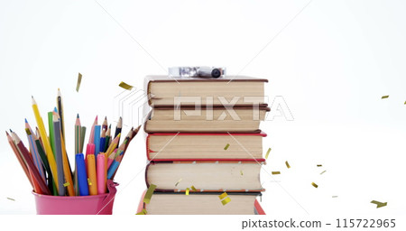Image of confetti falling over colour pencils and stack of books 115722965