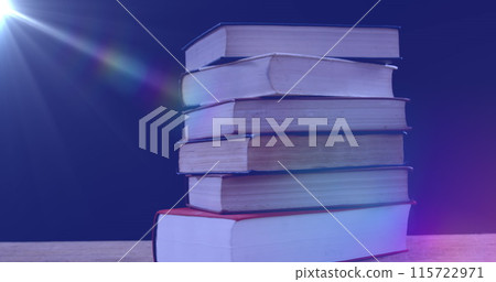 Image of glowing light over stack of books on blue background Image of glowing light over stack of books on blue background 115722971