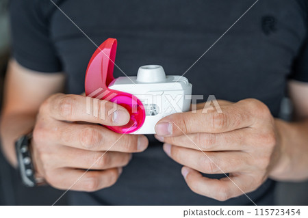 Close up view of man using medicine dry powder inhaler for treatment asthma or COPD diseases. Pharmaceutical product is used to treat lung inflammation and prevent asthma attack. Close up view of man using medicine dry powder inhaler for treatment asthma or COPD diseases. Pharmaceutical product is used to treat lung inflammation and prevent asthma attack. 115723454