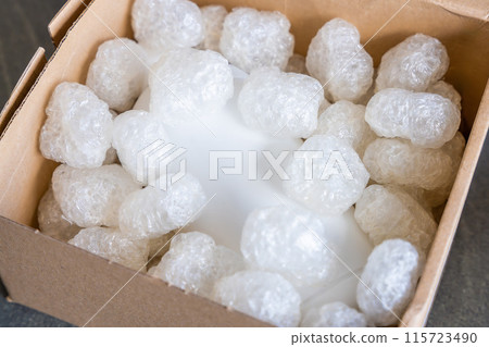 Eco packaging of parcels and white biodegradable filler. Box is filled with a filler safety for environment. Delivery of goods, parcels, delivery service, nature protection and recycling concept 115723490