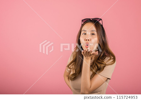 Asian happy portrait beautiful cute young woman teen standing blowing kiss air something on palm hands expresses her love looking to camera studio shot isolated on pink background with copy space Asian happy portrait beautiful cute young woman teen standing blowing kiss air something on palm hands expresses her love looking to camera studio shot isolated on pink background with copy space 115724953