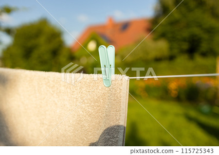 Recently washed clothes are hung along the line to dry with colorful plastic clothespins at lunchtime. Concept of everyday household items. 115725343