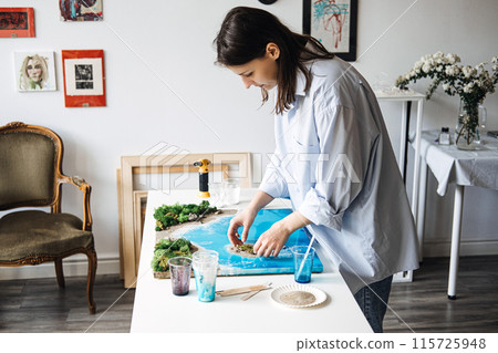 Artist Crafting an Epoxy Resin Landscape in Her Studio 115725948