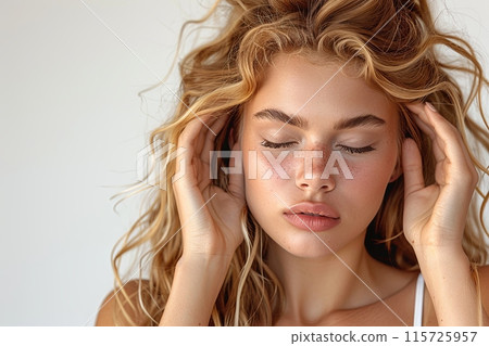 Young woman holds her head, closing her eyes from pain and discomfort on a white background Young woman holds her head, closing her eyes from pain and discomfort on a white background 115725957