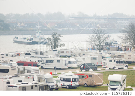 RV camper van parking place at Warnemunde Rostock harbor canal cruise liner pier ferry vessel ship background. Many recreational vehicle parked Germany port harbor foggy day. Travel tourism adventure 115726313