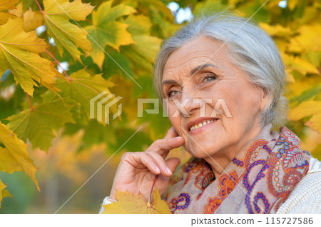 Senior nice woman walking in the park in autumn.  115727586