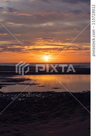 The golden sunset casting its glow on the calm beach creates a truly mesmerizing view The golden sunset casting its glow on the calm beach creates a truly mesmerizing view 115728012