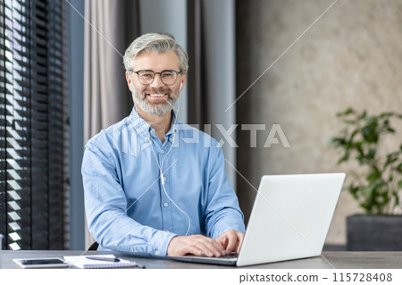 Smiling mature man with glasses working on laptop in modern office environment, exuding confidence and professionalism. Smiling mature man with glasses working on laptop in modern office environment, exuding confidence and professionalism. 115728408