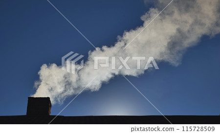 Silhouette of smoke against blue sky from the chimney of a village house. Silhouette of smoke against blue sky from the chimney of a village house. 115728509